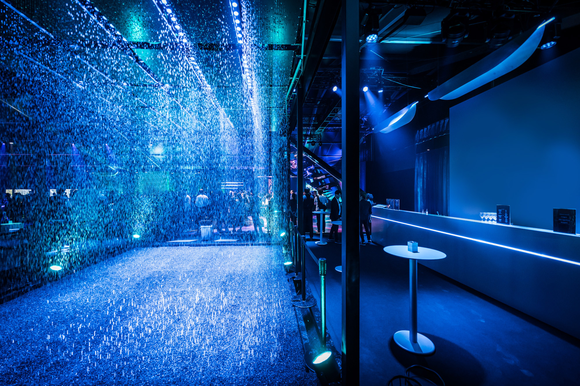 Futuristic event space featuring an illuminated water curtain, sleek bar area, and ambient blue lighting Battle Royal Studios