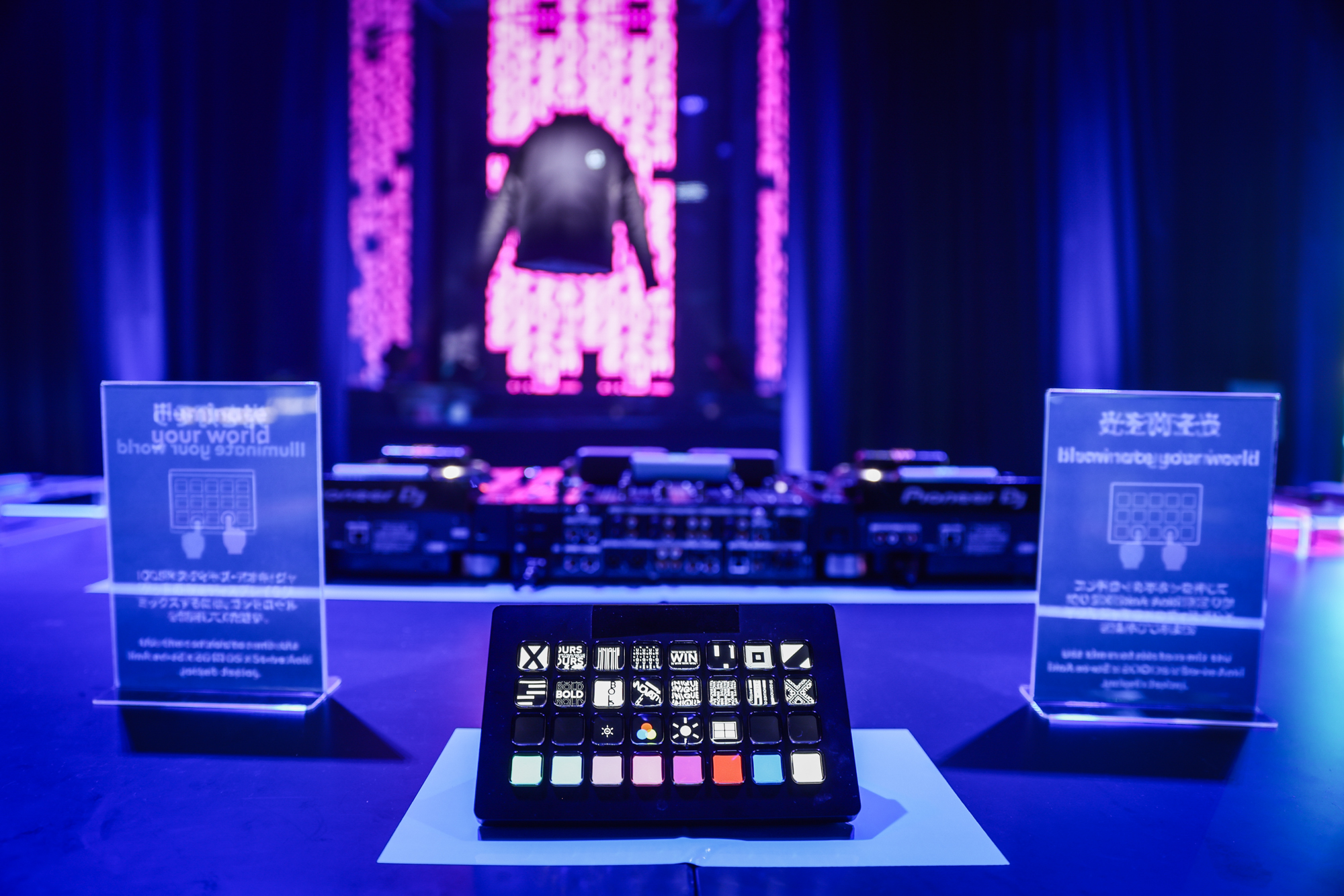 Interactive control panel with illuminated buttons at a futuristic event setup, featuring a glowing jacket display in the background Battle Royal Studios